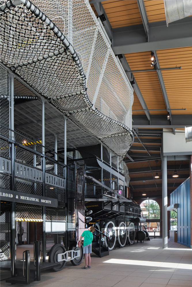 Kid playing near large indoor play structure with interactive elements