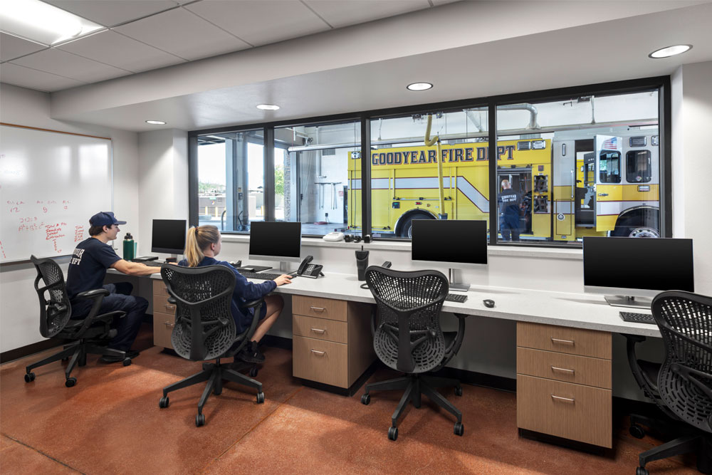 Firefighters in report room looking into fire station bays